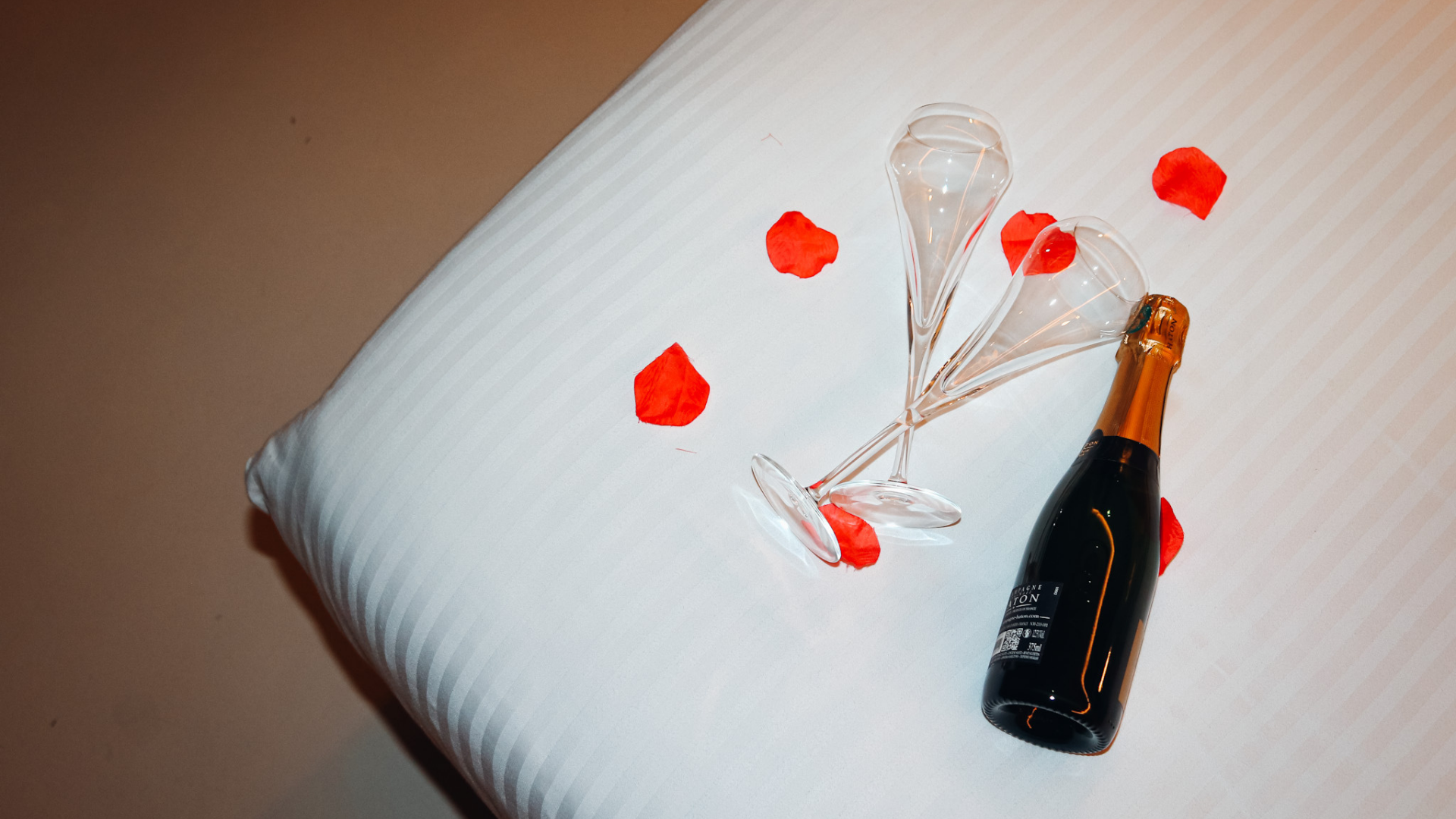 Champagne et pétales sur lit blanc.