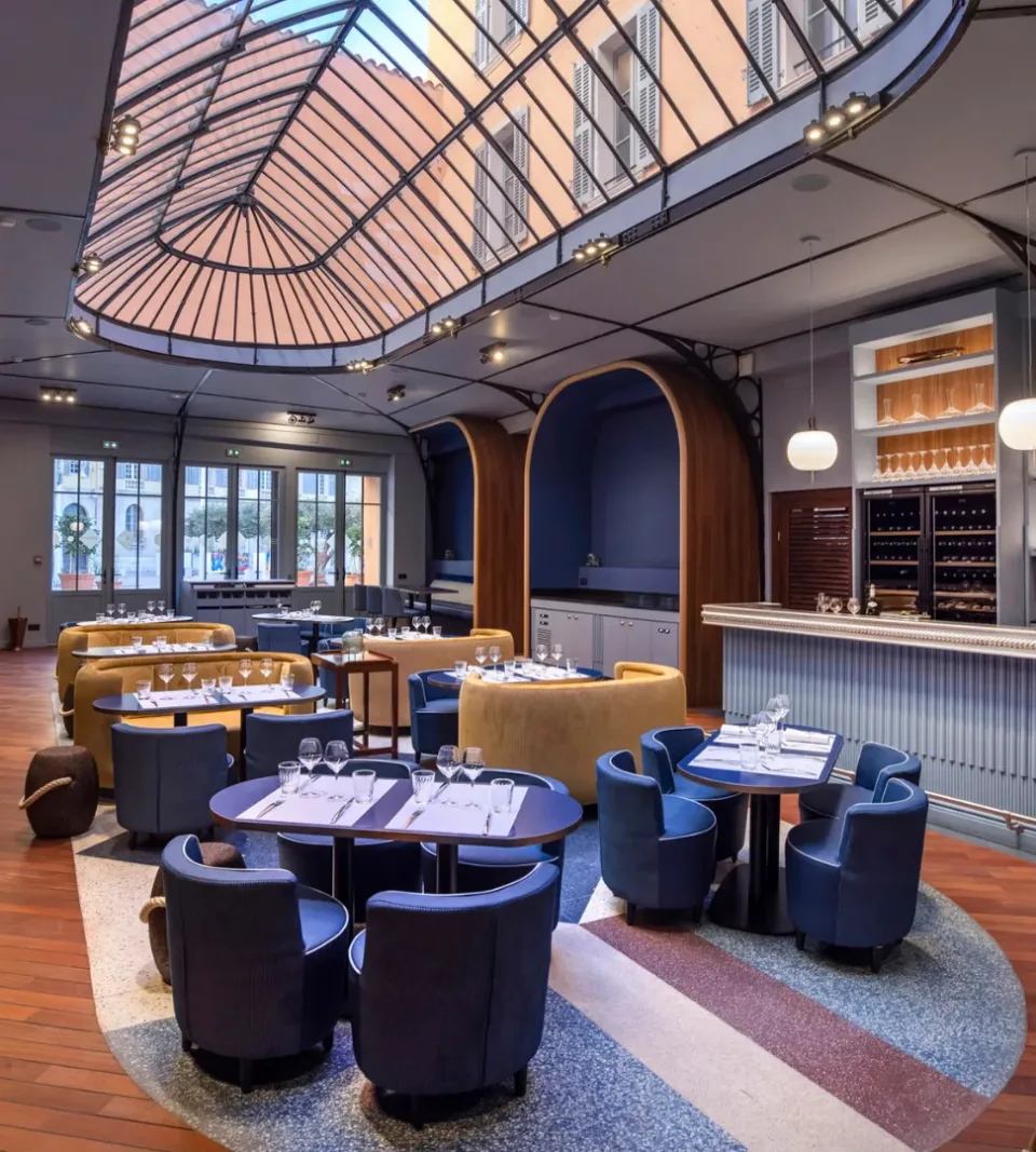 Restaurant moderne avec verrière et tables élégantes.