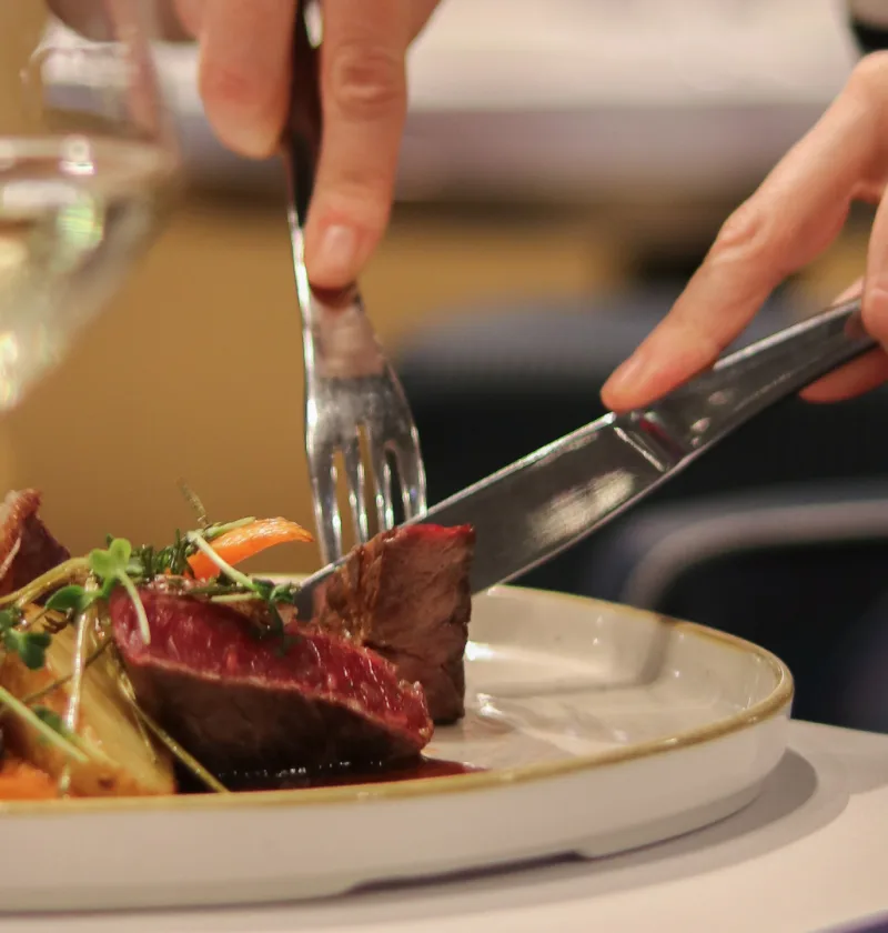 Main coupant de la viande à table élégante.