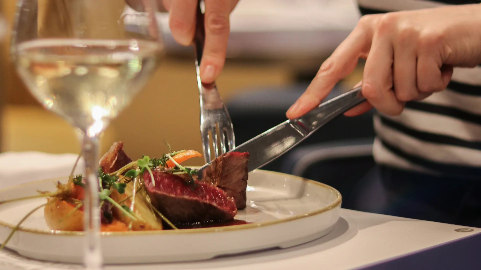 Main coupant de la viande à table élégante.