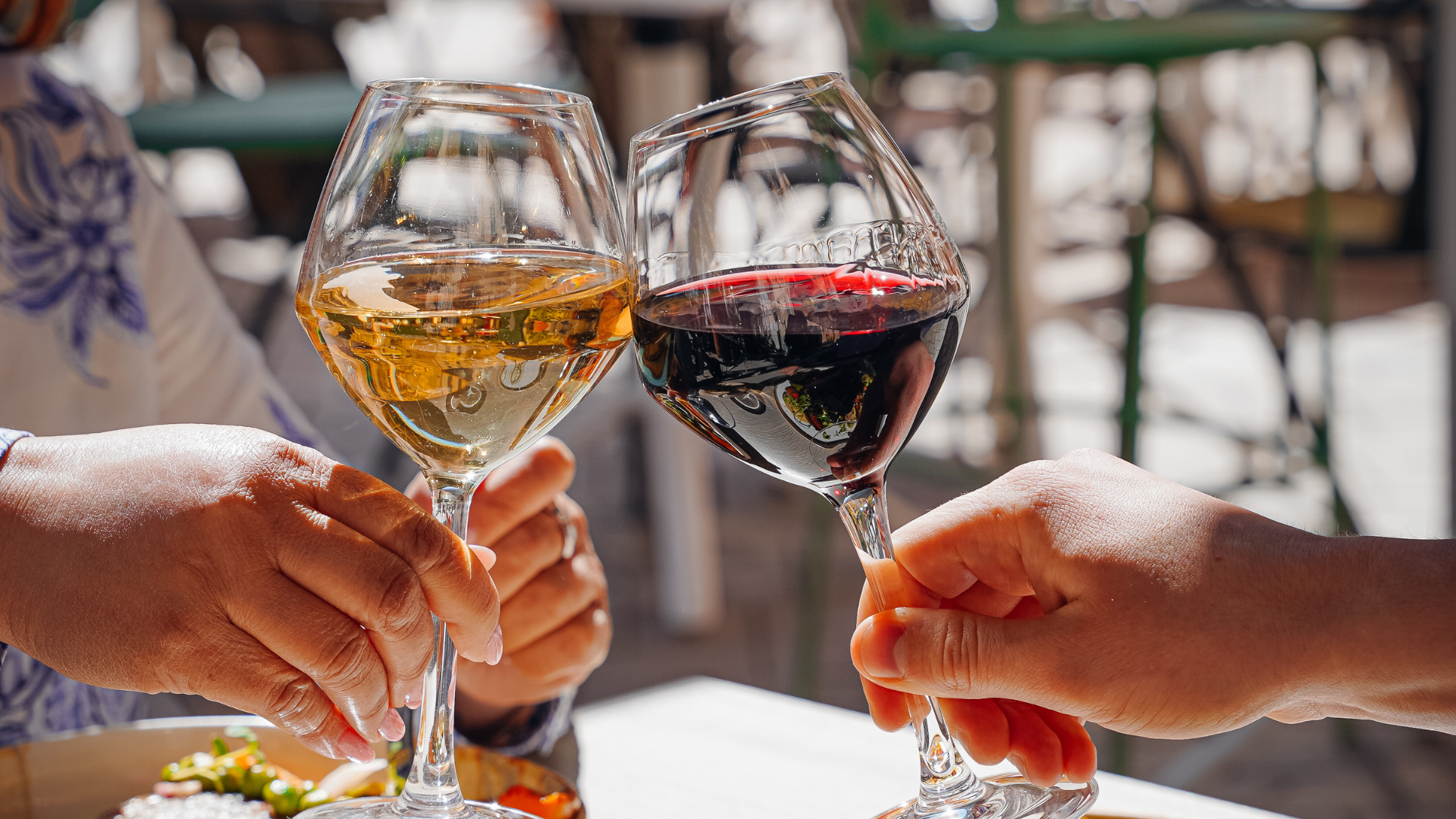 Deux verres de vin rouge et blanc trinqués.
