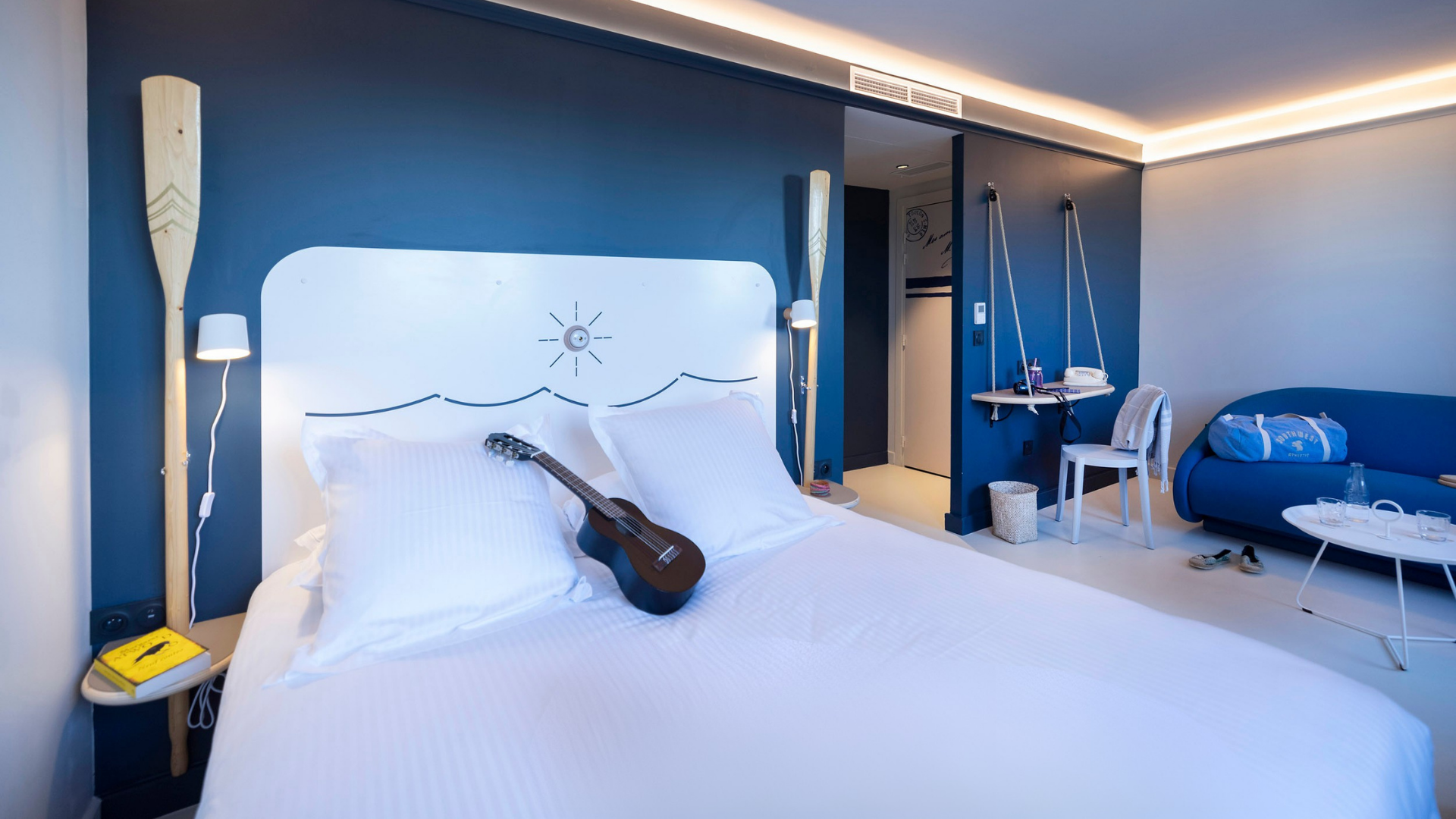 Chambre d'hôtel moderne avec guitare sur le lit.