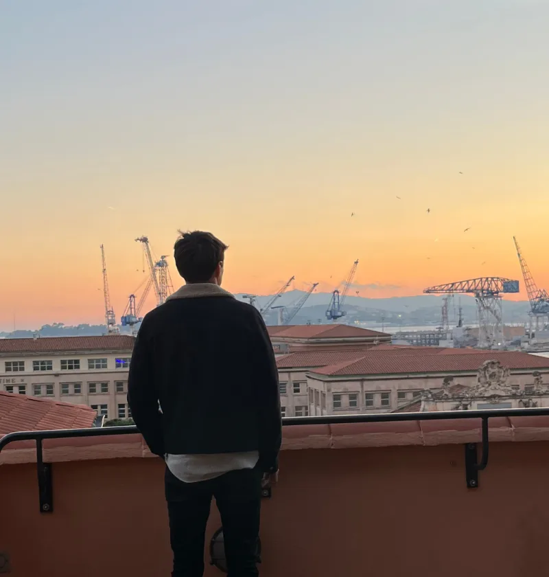 Homme regardant un coucher de soleil sur le port.
