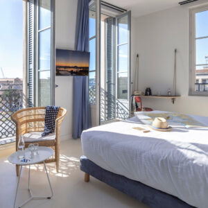 Chambre lumineuse avec vue extérieure et mobilier confortable.