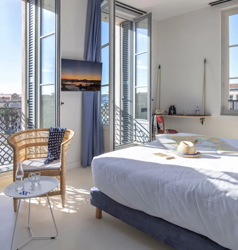 Chambre lumineuse avec vue extérieure et mobilier confortable.